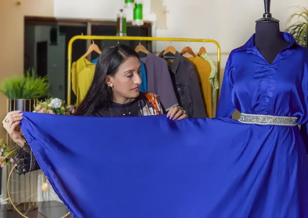 A designer selecting colorful fabrics and textures from a textile display — representing a professional fabric sourcing service for custom tailoring and dress designing.